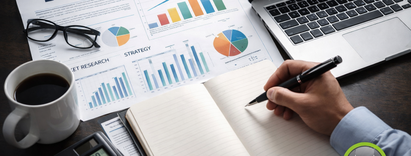 Foto einer Gastronomie Businessplan-Szene mit Laptop, Diagrammen, Notizbuch, Taschenrechner und einer Hand, die schreibt. In der unteren rechten Ecke befindet sich das Gastro Piraten Logo.