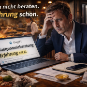Mann im Business-Outfit sitzt in einem hektischen Restaurant vor einem Laptop mit dem Text „Gastronomieberatung Erfahrung mit KI“, während im Hintergrund der laufende Betrieb und Stress in Küche und Service zu sehen sind