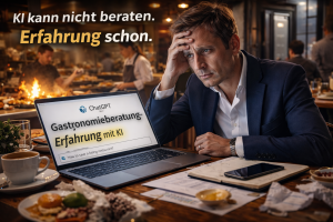 Mann im Business-Outfit sitzt in einem hektischen Restaurant vor einem Laptop mit dem Text „Gastronomieberatung Erfahrung mit KI“, während im Hintergrund der laufende Betrieb und Stress in Küche und Service zu sehen sind